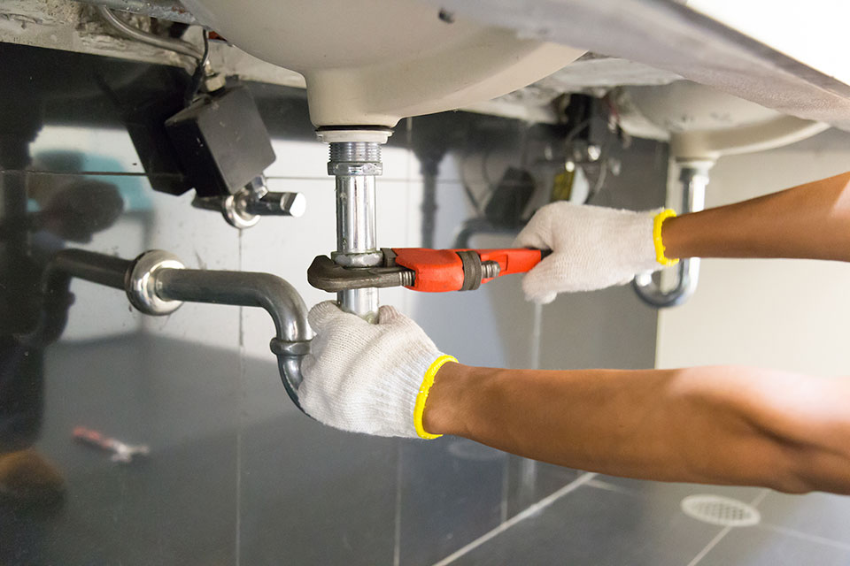 A plumber performing drain repair on a leaking drain