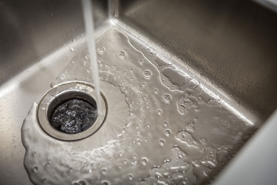 Water running into a garbage disposal during a garbage disposal repair