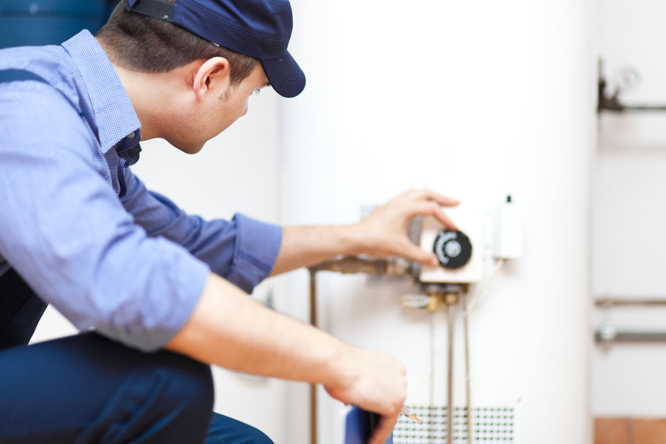 A plumber performing water heater repair on a white water heater